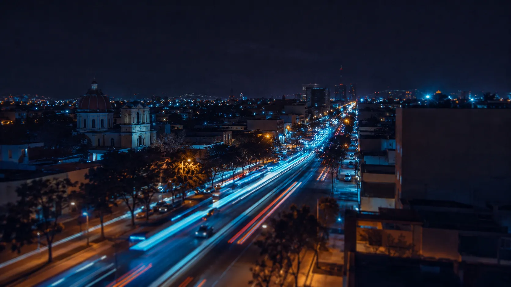 Avenida de una ciudad mexicana de noche con estelas de luces de autobuses